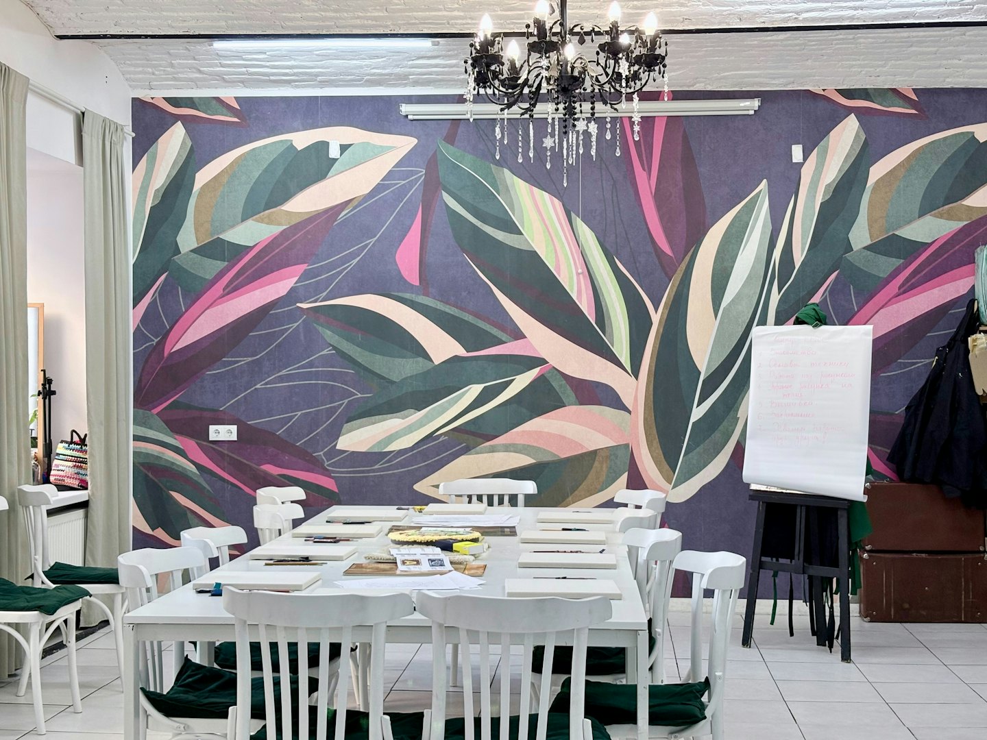 Empty workshop with art supplies on a table and tropical wallpaper.