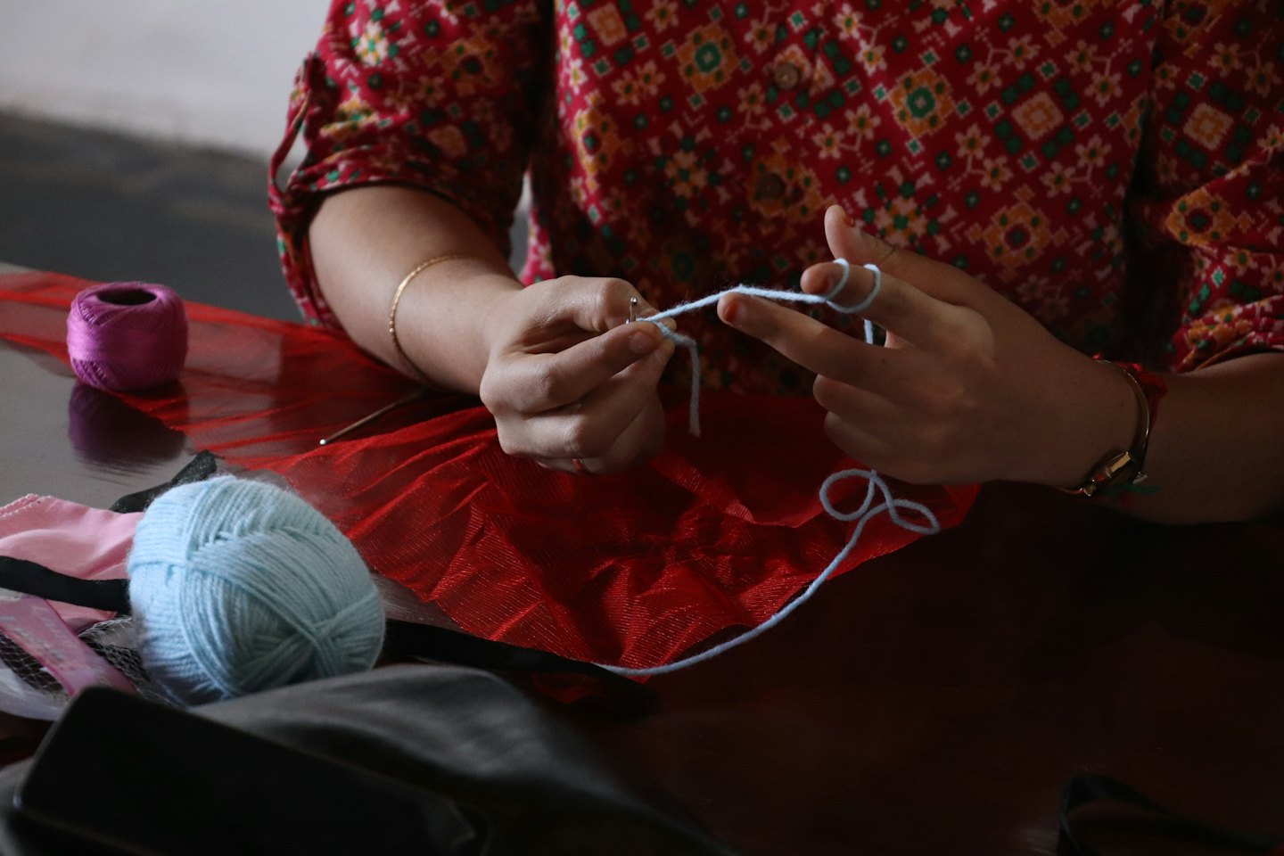 Hands crocheting with light blue yarn and a hook.