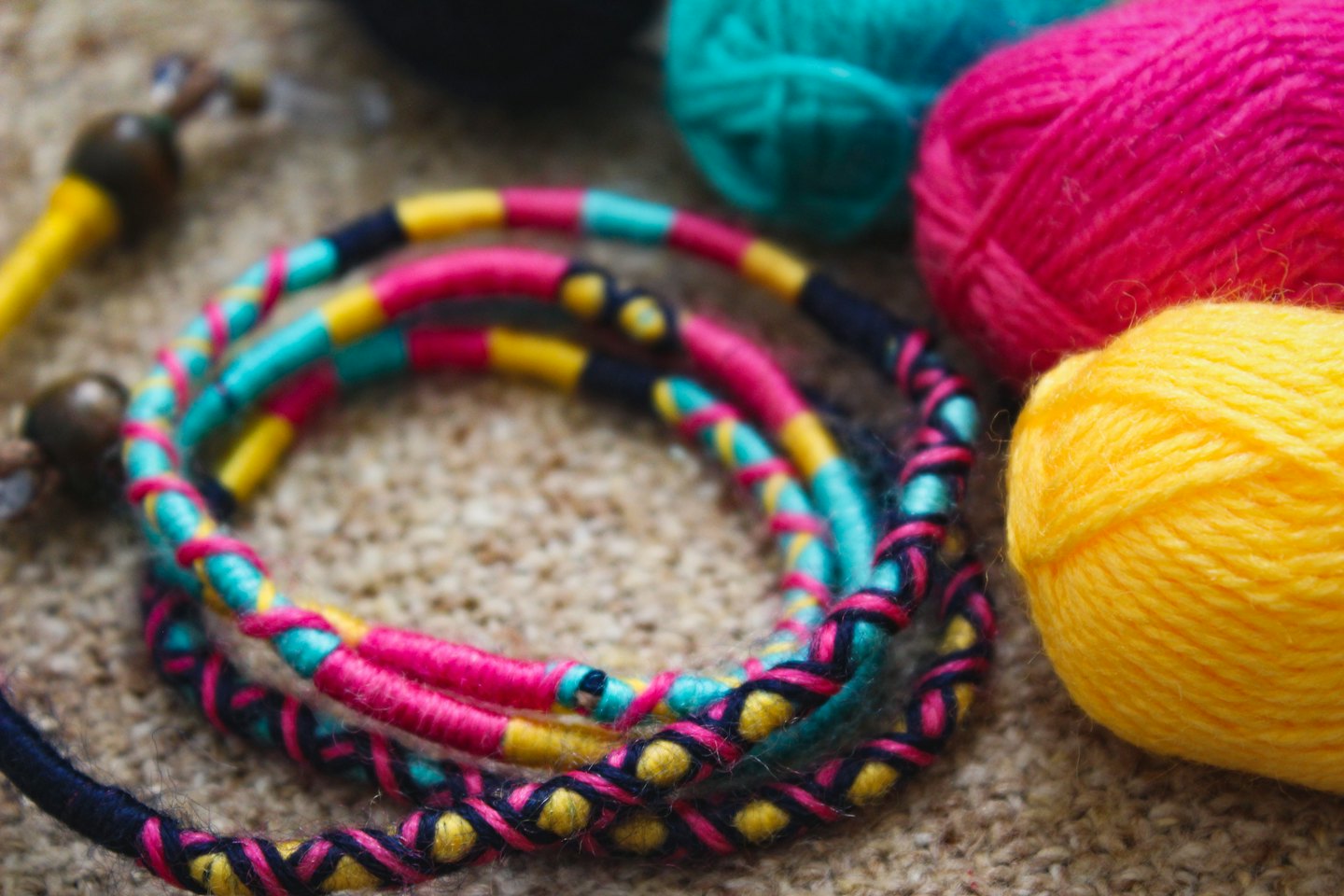 Colorful yarn balls and handmade crafts on a beige surface.