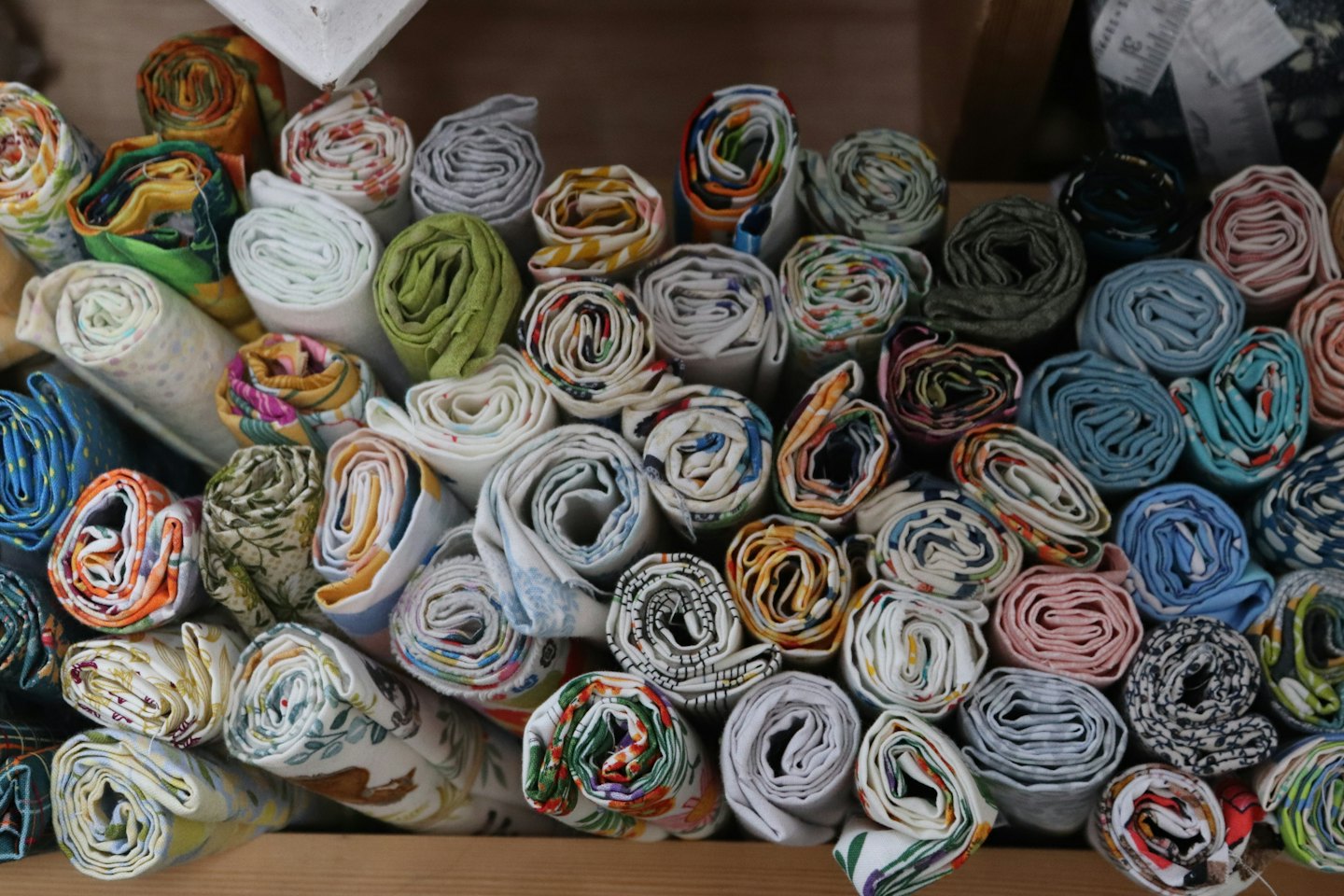 Colorful patterned fabric rolls stacked neatly on wooden shelves.