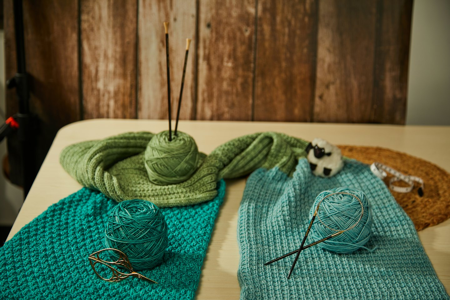Yarn balls, knitting needles, and crafting tools on a table.