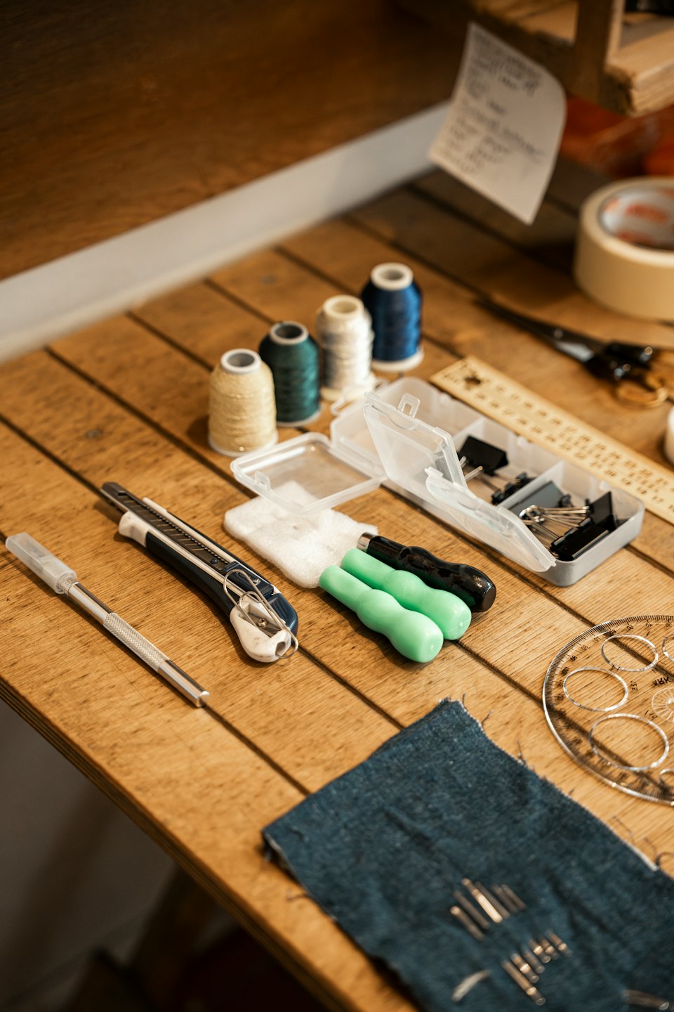 Crafting tools and fabric arranged on a wooden workbench.